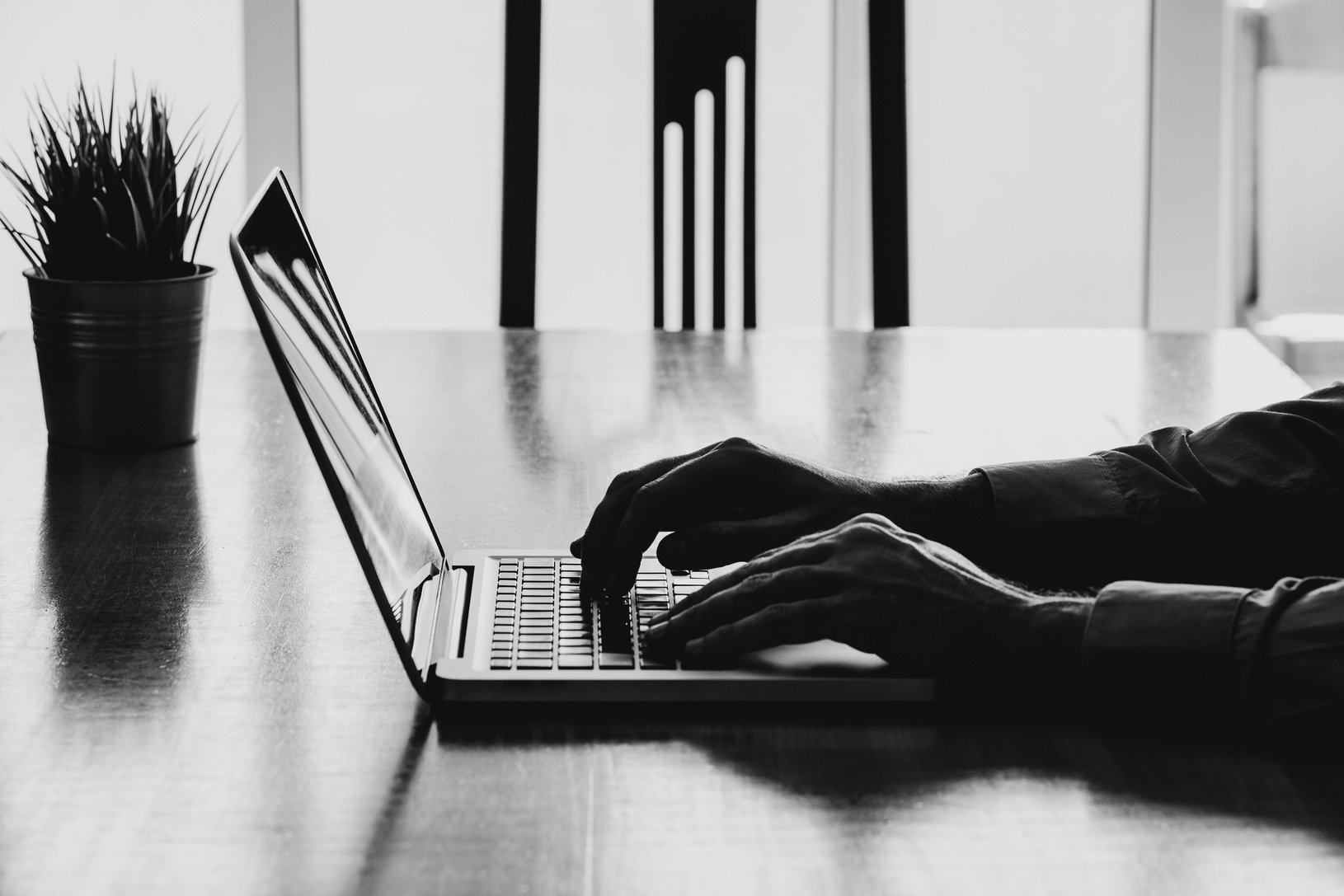 Man hands typing on a laptop in a workplace. Business black and white.